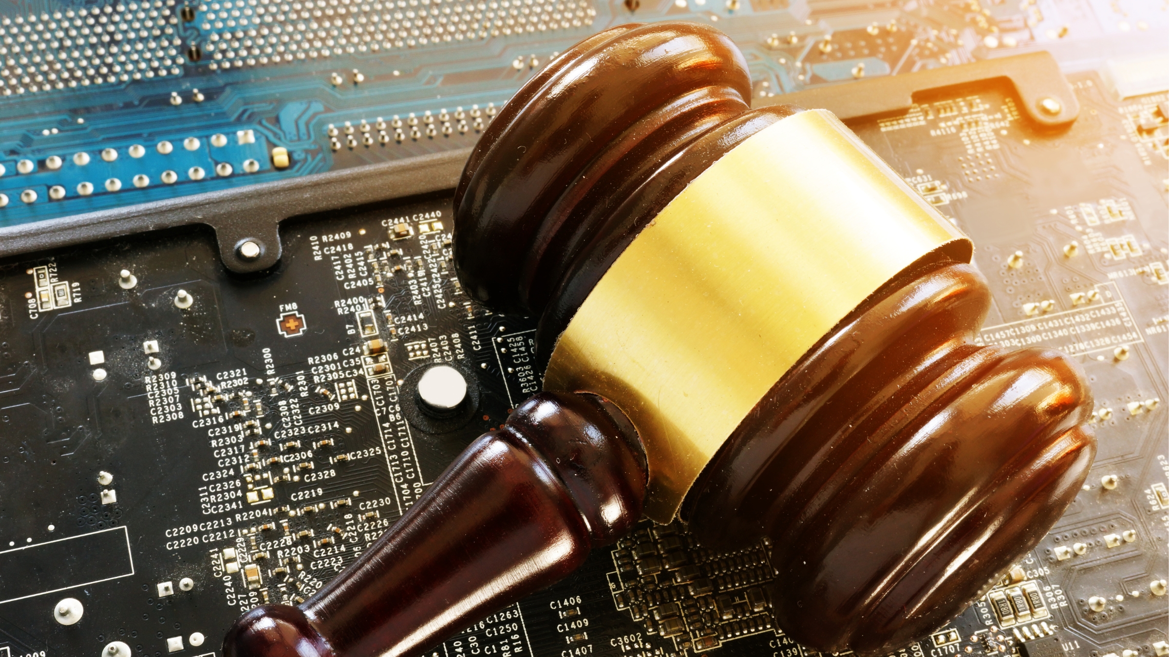 Judge’s gavel resting on a computer circuit board, symbolising the intersection of law, technology and online regulation.